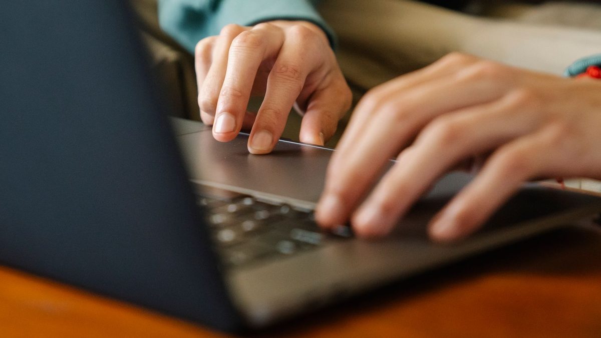 Dłonie na klawiaturze i gładziku laptopa