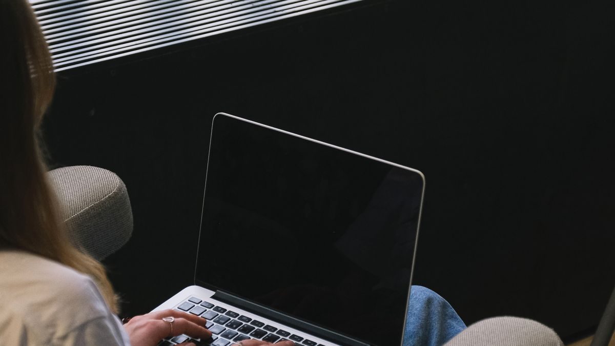 Dłonie na klawiaturze laptopa w przyciemnionym pokoju