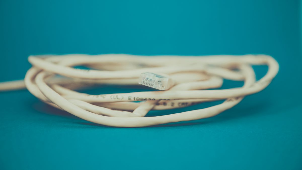 Zwinięty kabel sieciowy na turkusowym tle