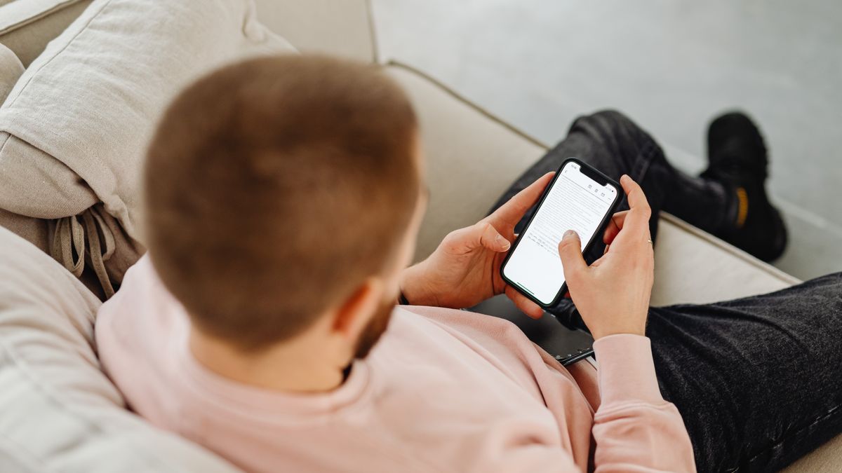 Mężczyzna na kanapie czyta wiadomość w telefonie